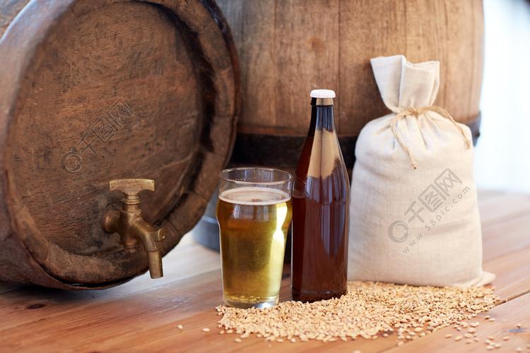 啤酒厂饮料和酒精的概念关闭旧啤酒桶玻璃瓶子和袋子用木制的桌子上的